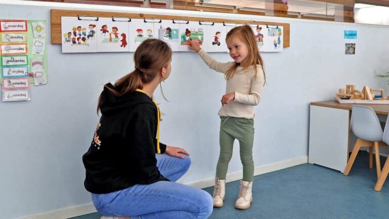 A woman and a child in a classroom looking at a wall.